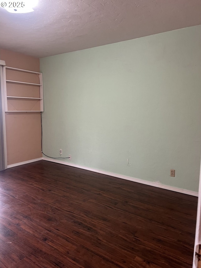 2711 Bowman Rd, Reedsport, OR 97467 - unfurnished bedroom featuring dark wood-type flooring and baseboards