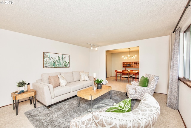 carpeted living room with a textured ceiling, a chandelier, and track lighting