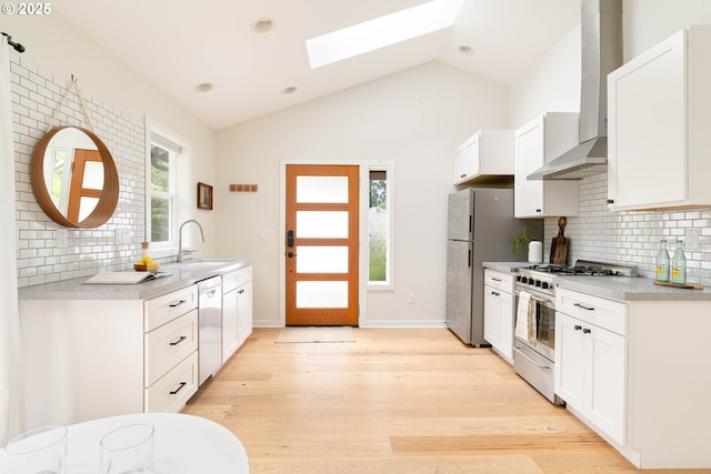 8160 SW 41st Ave, Portland, OR 97219 - kitchen with appliances with stainless steel finishes, wall chimney exhaust hood, a skylight, vaulted ceiling, and decorative backsplash