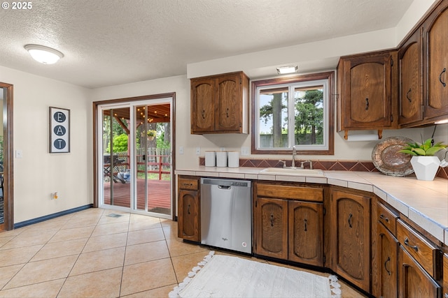 15648 NE Rose Pkwy, Portland, OR 97230 - kitchen with stainless steel dishwasher, a sink, a textured ceiling, tile countertops, and light tile patterned flooring