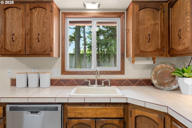 15648 NE Rose Pkwy, Portland, OR 97230 - kitchen featuring stainless steel dishwasher, a sink, brown cabinets, and tile countertops
