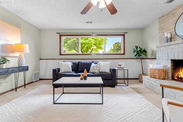 15648 NE Rose Pkwy, Portland, OR 97230 - living area featuring a textured ceiling, a ceiling fan, a stone fireplace, and baseboards