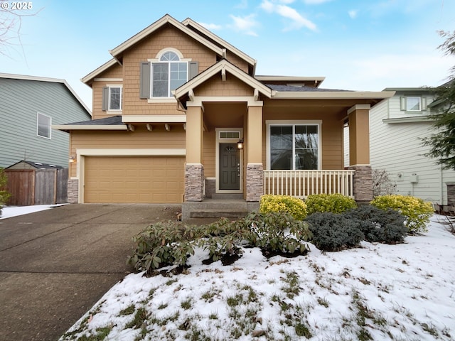 craftsman-style home featuring driveway, stone siding, an attached garage, and covered porch