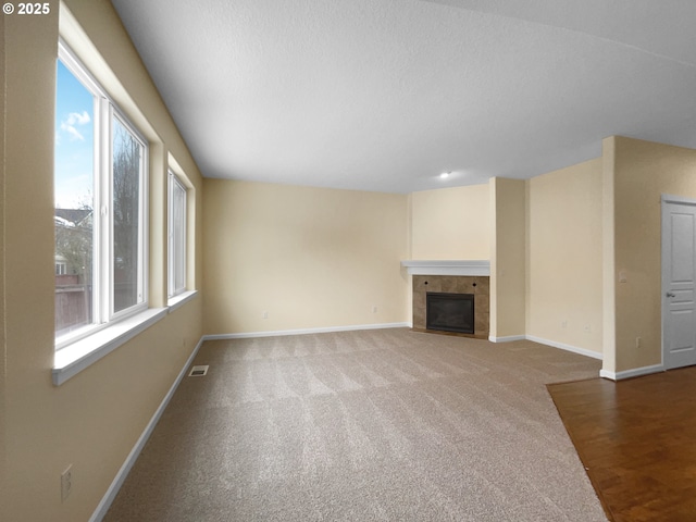 unfurnished living room featuring carpet floors, visible vents, a fireplace, and baseboards