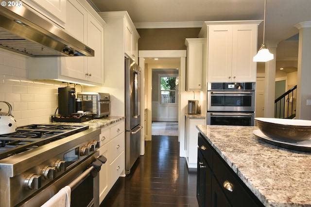 3225 SE Lincoln St, Portland, OR 97214 - kitchen featuring under cabinet range hood, appliances with stainless steel finishes, dark wood-style floors, white cabinets, and ornamental molding