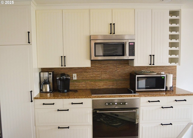 kitchen featuring appliances with stainless steel finishes, backsplash, white cabinetry, and dark stone counters