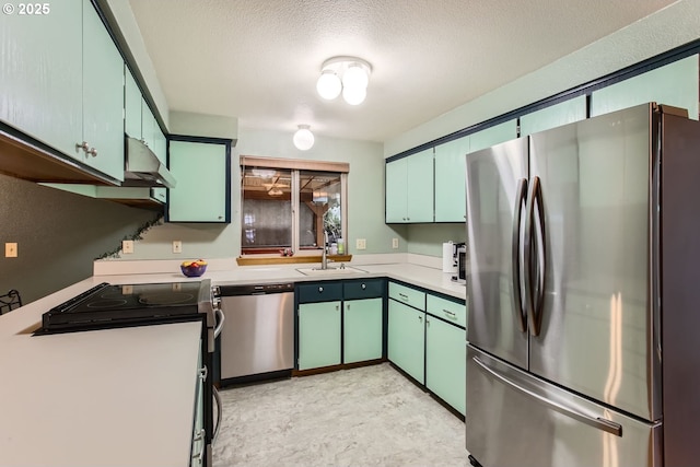 kitchen with a textured ceiling, under cabinet range hood, a sink, light countertops, and appliances with stainless steel finishes