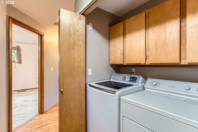 laundry room with washer and clothes dryer, light wood-type flooring, and cabinet space