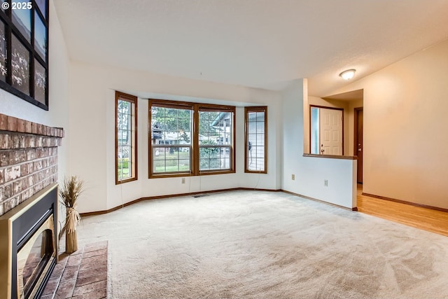 unfurnished living room with carpet, a brick fireplace, visible vents, and baseboards