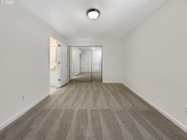 unfurnished bedroom with ensuite bath, baseboards, and carpet