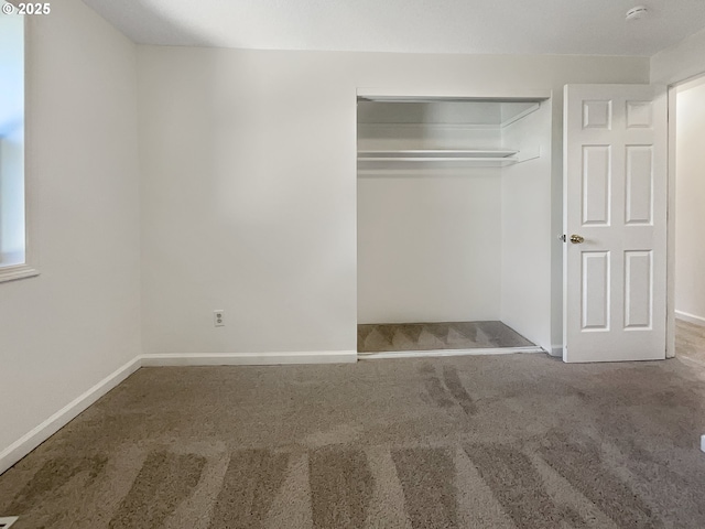 unfurnished bedroom featuring carpet, a closet, and baseboards