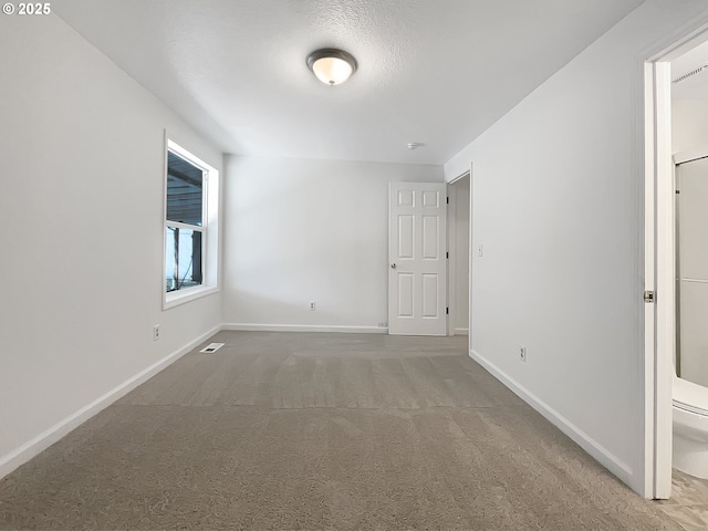 carpeted spare room with visible vents and baseboards