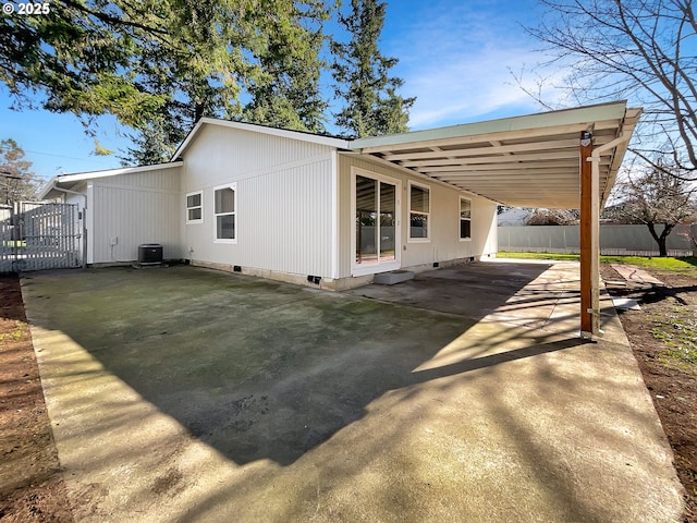 back of house featuring fence, driveway, a carport, crawl space, and central air condition unit