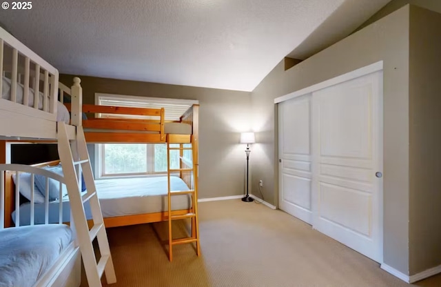 carpeted bedroom with baseboards, lofted ceiling, and a closet