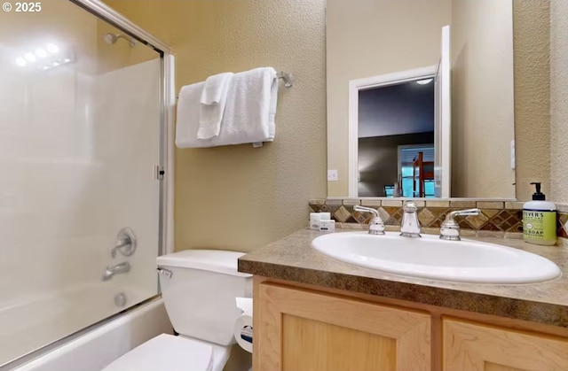 bathroom with vanity, a textured wall, bath / shower combo with glass door, and toilet