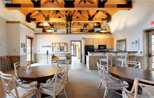 dining space featuring wainscoting, beam ceiling, and a healthy amount of sunlight