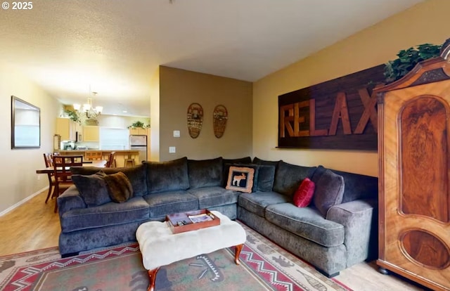 living room featuring baseboards, a chandelier, and wood finished floors