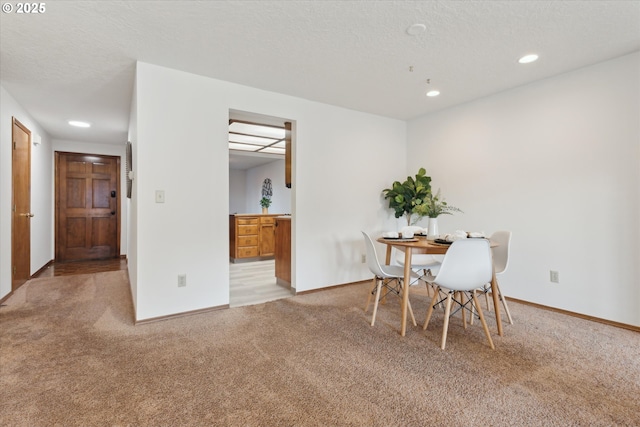 dining room with a textured ceiling and light colored carpet