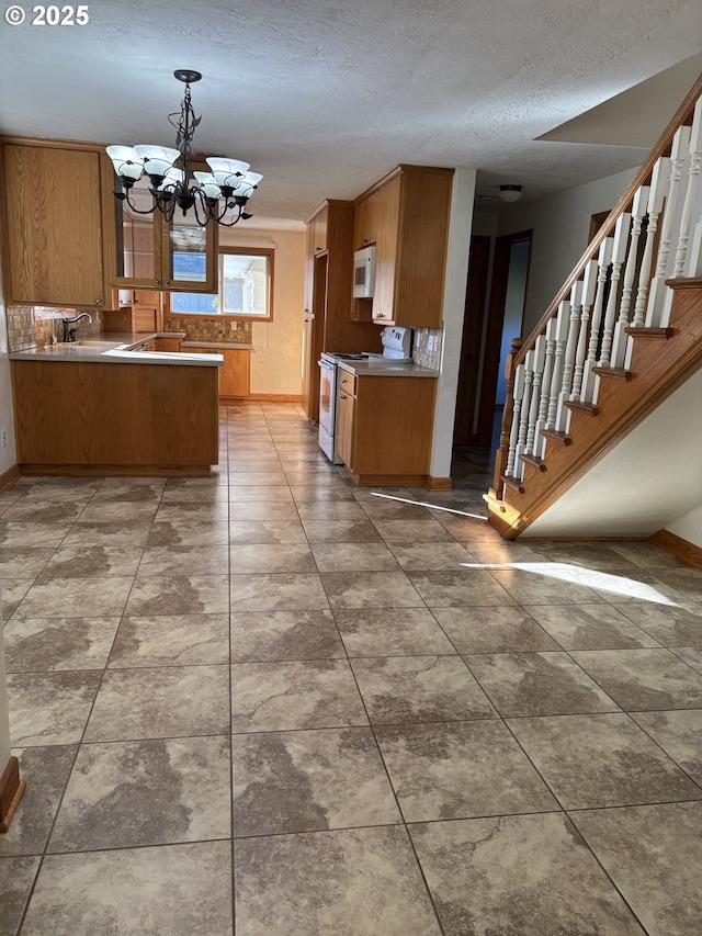 11623 Broadacres Rd NE, Hubbard, OR 97032 - kitchen with baseboards, brown cabinetry, white appliances, and a chandelier
