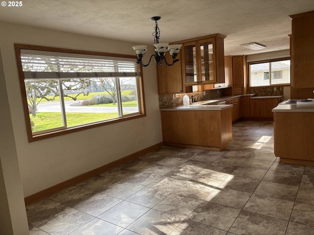 11623 Broadacres Rd NE, Hubbard, OR 97032 - kitchen featuring decorative backsplash, brown cabinets, baseboards, a peninsula, and a chandelier