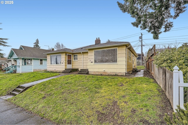 view of front of house with a front lawn, a chimney, and fence