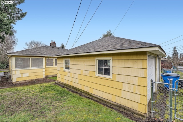 view of side of home with a chimney, fence, a lawn, and roof with shingles