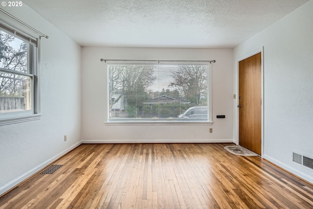 spare room featuring visible vents, a textured ceiling, and wood finished floors