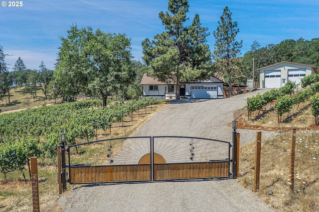 view of front facade featuring a rural view, a detached garage, fence, and a gate