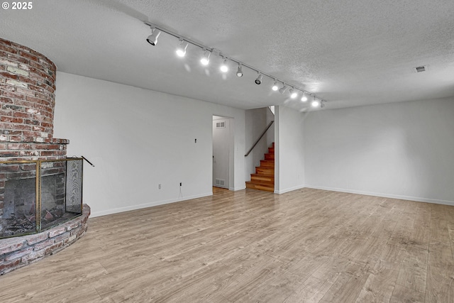 4729 SE Concord Rd, Milwaukie, OR 97267 - unfurnished living room with track lighting, stairway, a textured ceiling, baseboards, and wood finished floors