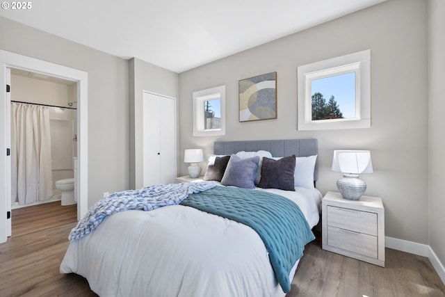 bedroom featuring baseboards, a closet, wood finished floors, and ensuite bathroom