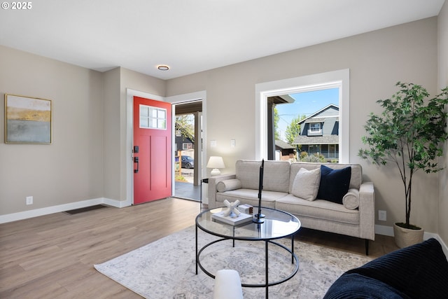 living room with baseboards, a wealth of natural light, and light wood-style flooring