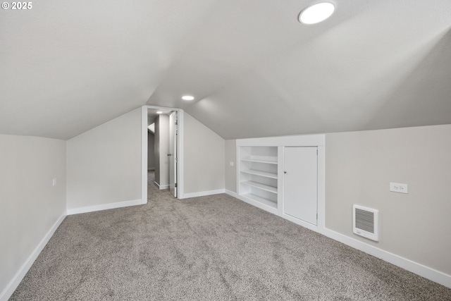 additional living space with vaulted ceiling, baseboards, carpet floors, and built in shelves