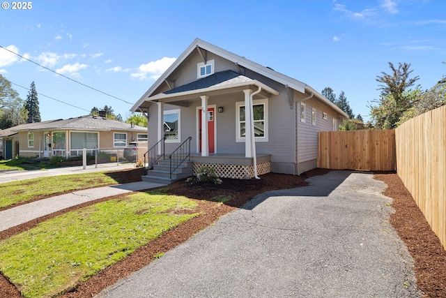 view of front facade with fence, driveway, and covered porch