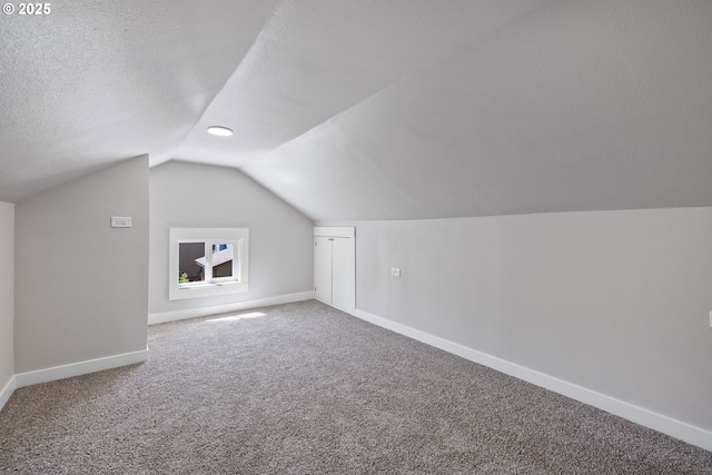 additional living space featuring vaulted ceiling, baseboards, carpet, and a textured ceiling