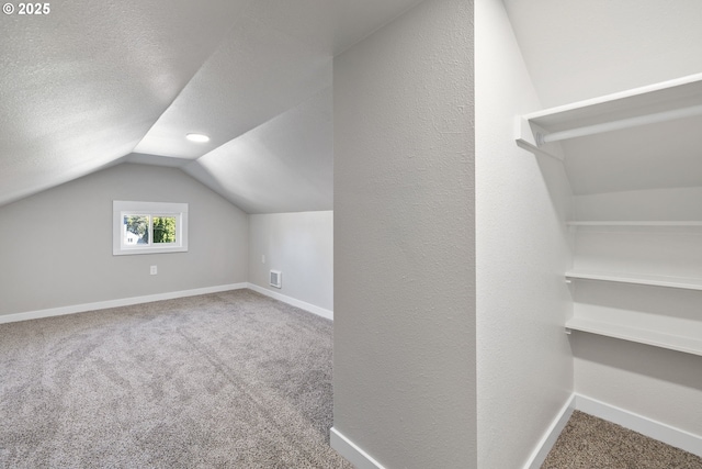 bonus room featuring a textured ceiling, carpet, baseboards, lofted ceiling, and visible vents