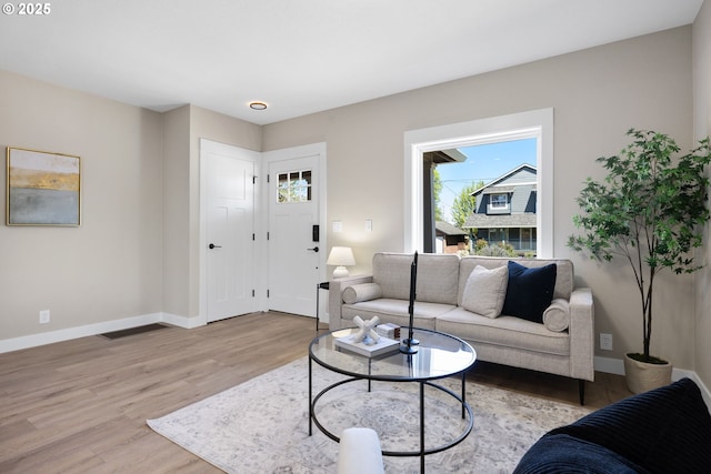 living area featuring baseboards and light wood-type flooring
