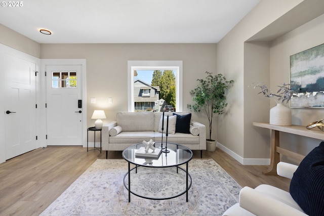 living area featuring baseboards, a healthy amount of sunlight, and light wood-style flooring