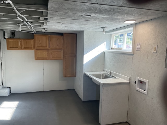 washroom with cabinet space, a textured wall, washer hookup, and a sink