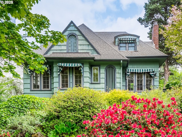 view of front of property featuring a shingled roof and a chimney