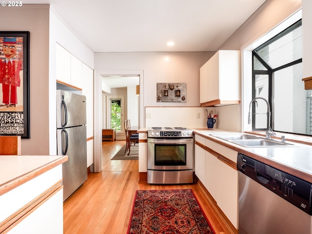 kitchen featuring white cabinets, appliances with stainless steel finishes, a sink, and light countertops