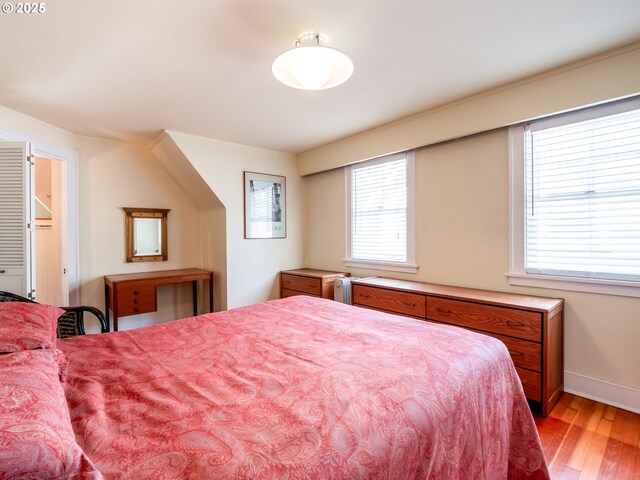 bedroom with baseboards, multiple windows, and wood finished floors