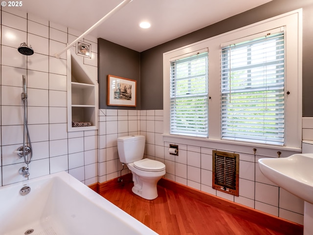 full bath with shower / bathtub combination, toilet, tile walls, and wood finished floors