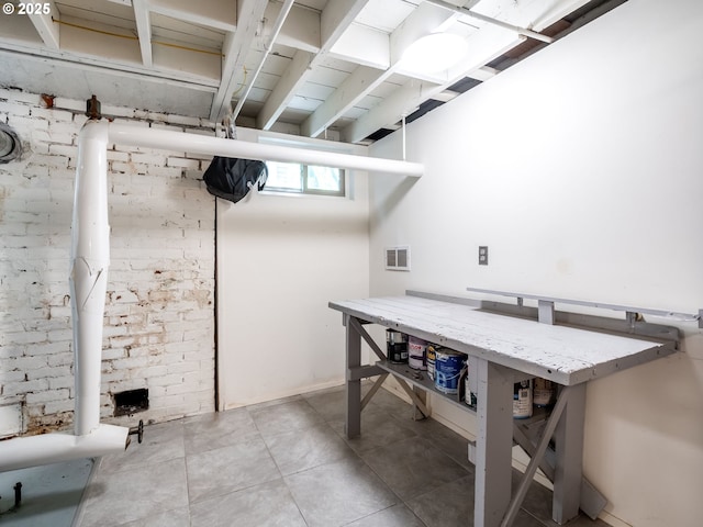 below grade area featuring visible vents, light tile patterned floors, and a workshop area