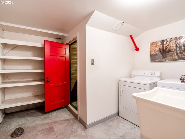 clothes washing area with light tile patterned floors, laundry area, washing machine and dryer, and a sink