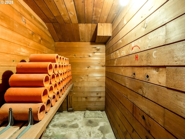wine area with wood walls, wooden ceiling, unfinished concrete floors, and a sauna