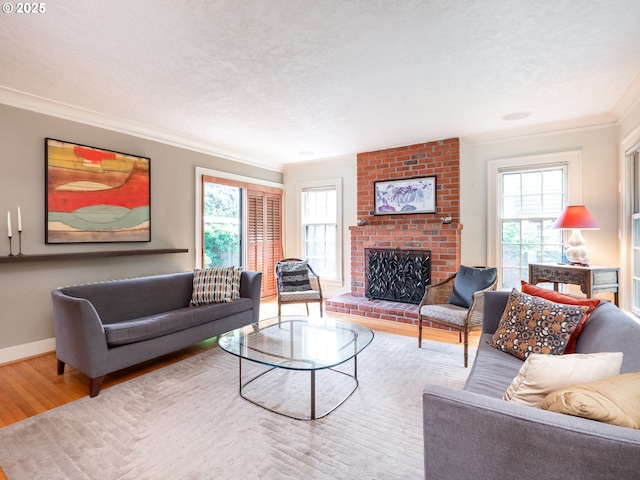 living area with a brick fireplace, baseboards, ornamental molding, and wood finished floors