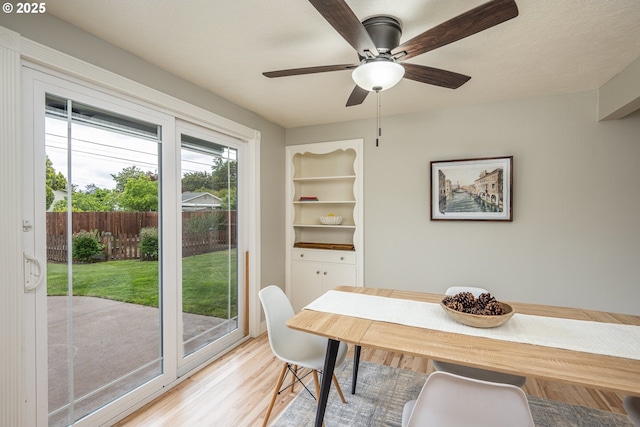 dining area featuring light wood-style flooring, a ceiling fan, and built in features
