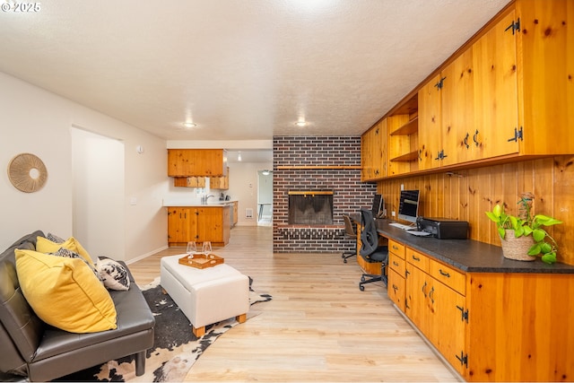 home office with light wood-style flooring, a fireplace, and a sink