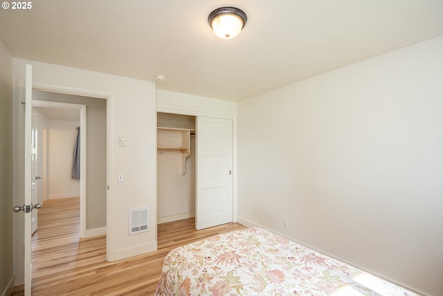 bedroom featuring light wood-type flooring, baseboards, and a closet