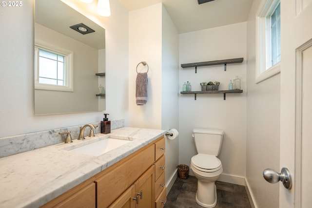 bathroom with toilet, baseboards, vanity, and wood finished floors